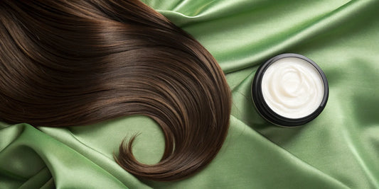 A jar of heat protectant and smoothing cream next to a lock of smooth hair.